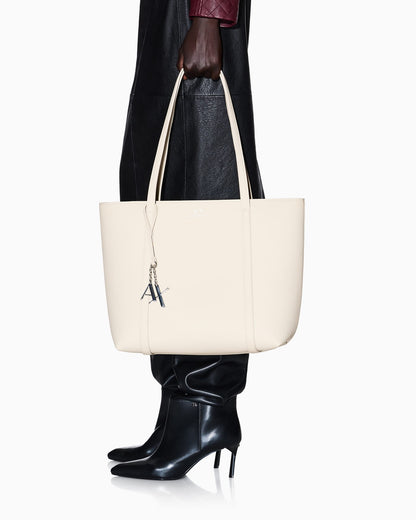Textured tote bag with handles and a decorative charm