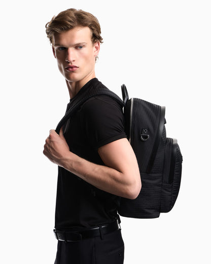 Backpack with a front zip pocket and a metal logo plaque